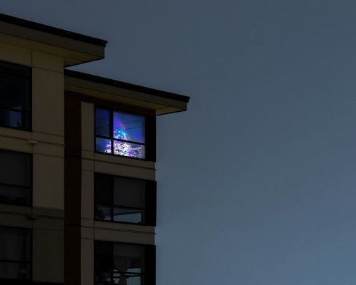 Person resting eyes by looking out of a high-rise apartment window