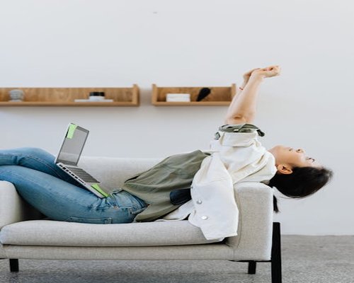 A professional woman stretching and looking away from her laptop screen to rest her eyes