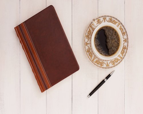 A cup of coffee and a notebook on an office table